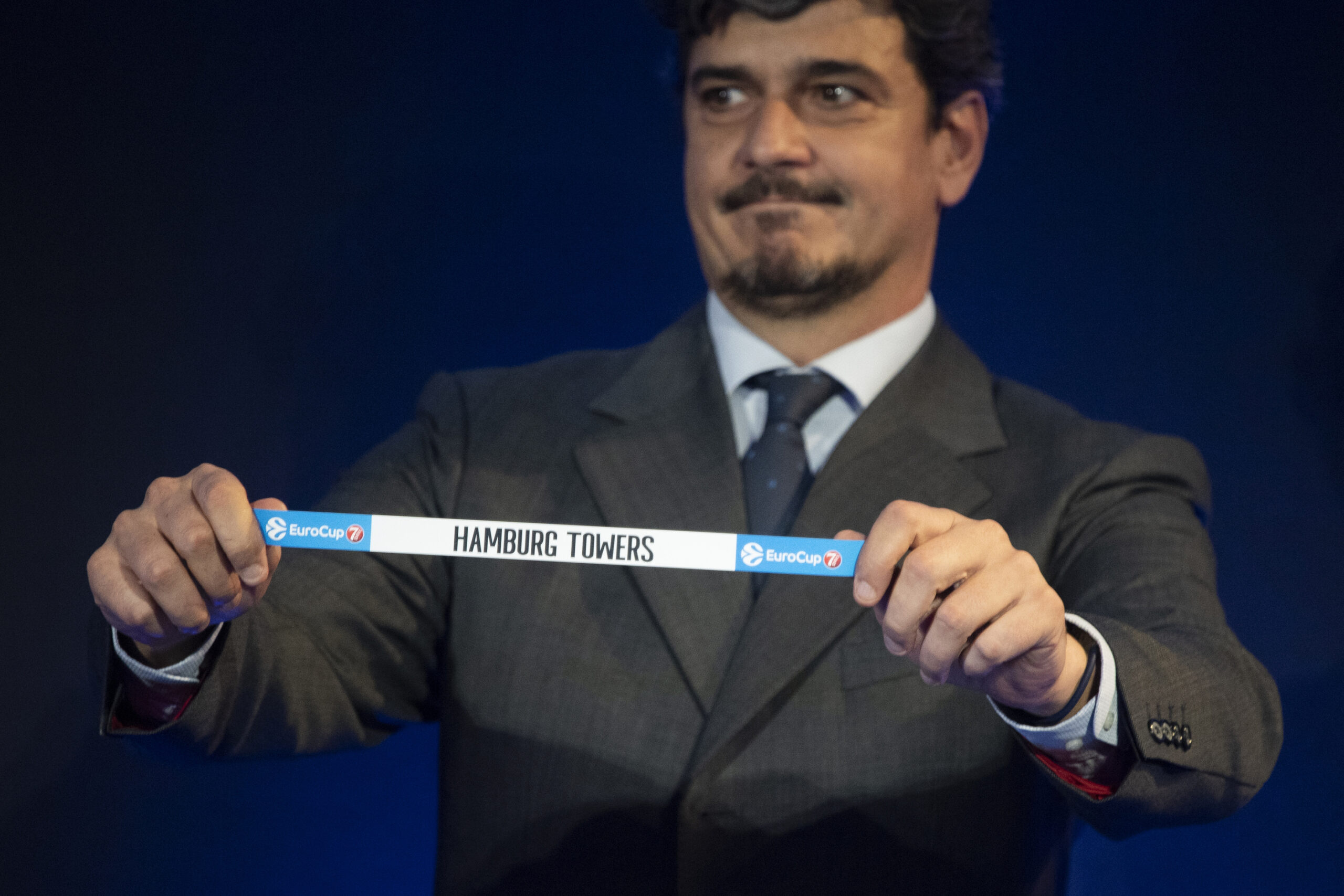 Mann in Anzug hält ein Band mit der Aufschrift 'HAMBURG TOWERS' bei einer EuroCup-Veranstaltung
