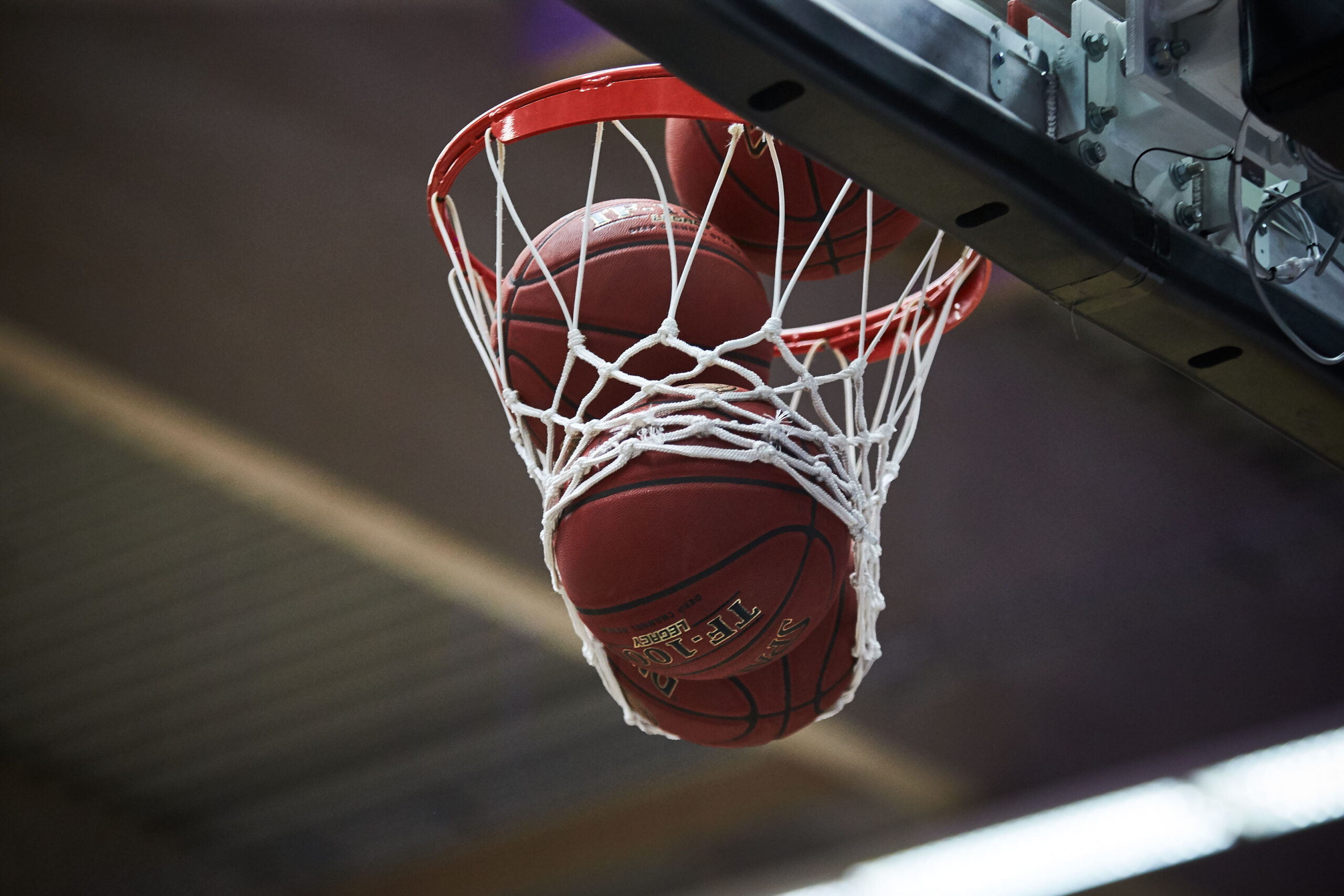 Zwei Basketballbälle, die gleichzeitig durch einen Basketballkorb mit Netz fallen