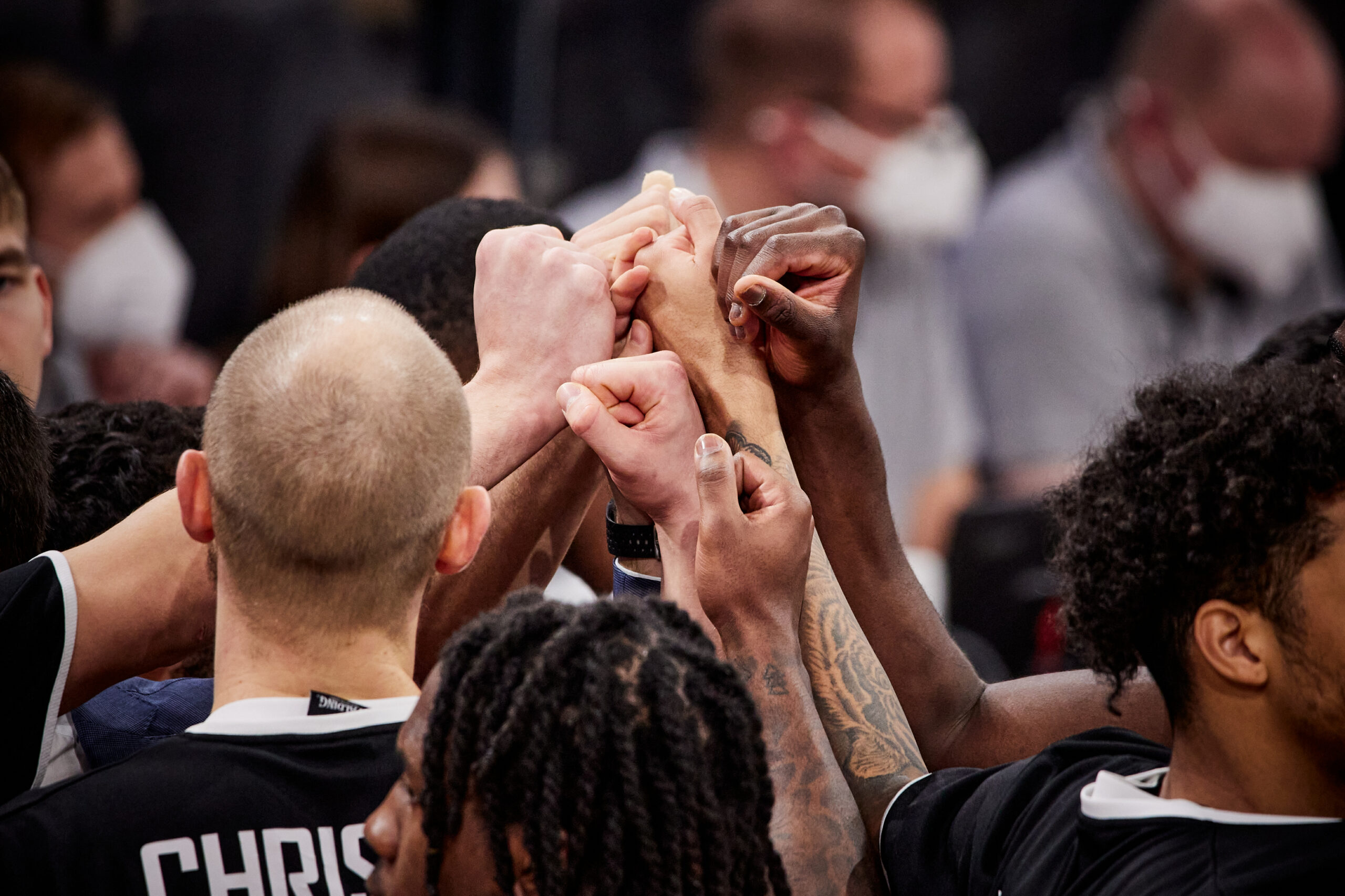 Basketballspieler bilden einen Teamkreis und legen ihre Hände in die Mitte als Zeichen des Zusammenhalts.