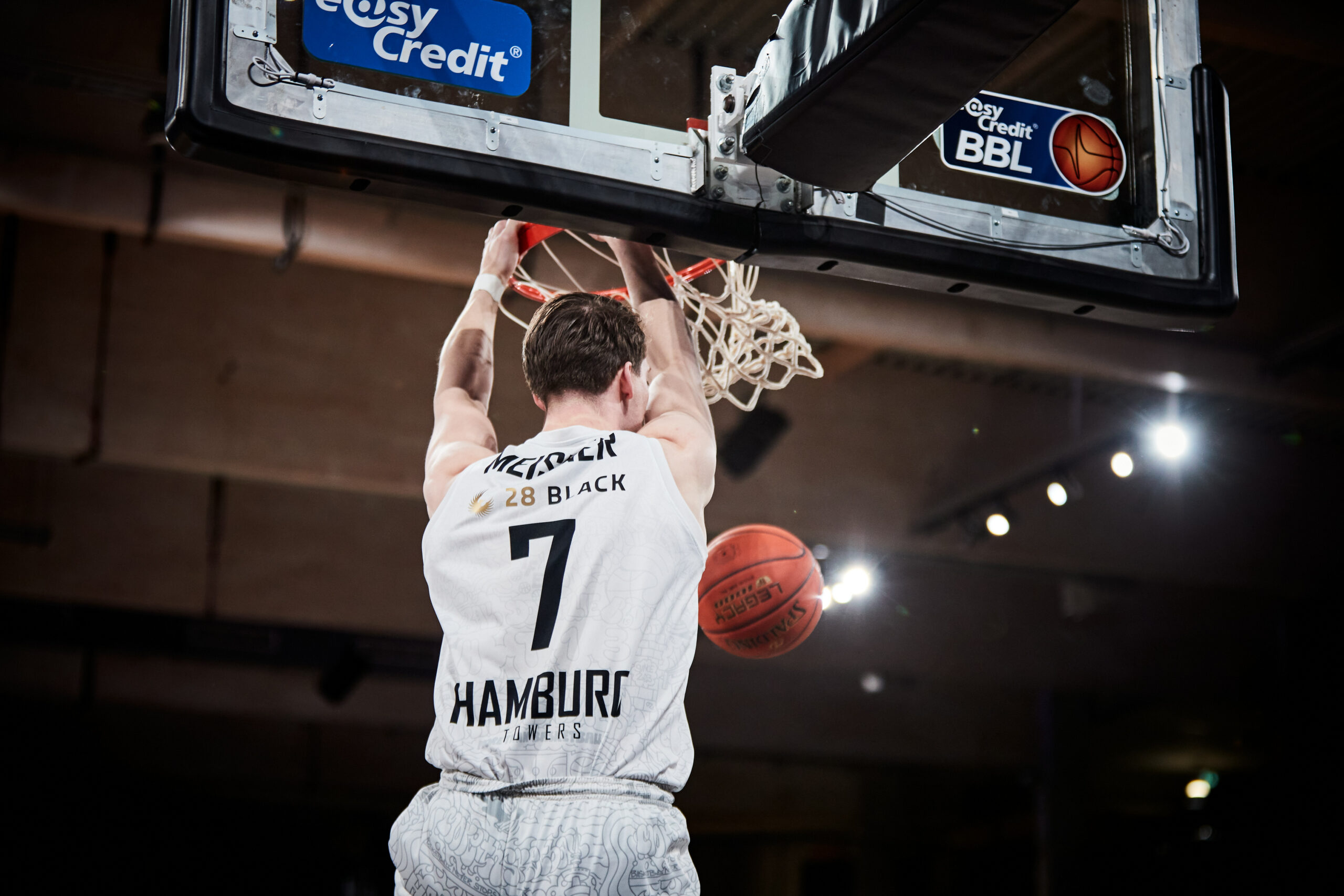 Basketballspieler der Hamburg Towers mit Trikotnummer 7 beim Dunk am Korb in einer Halle