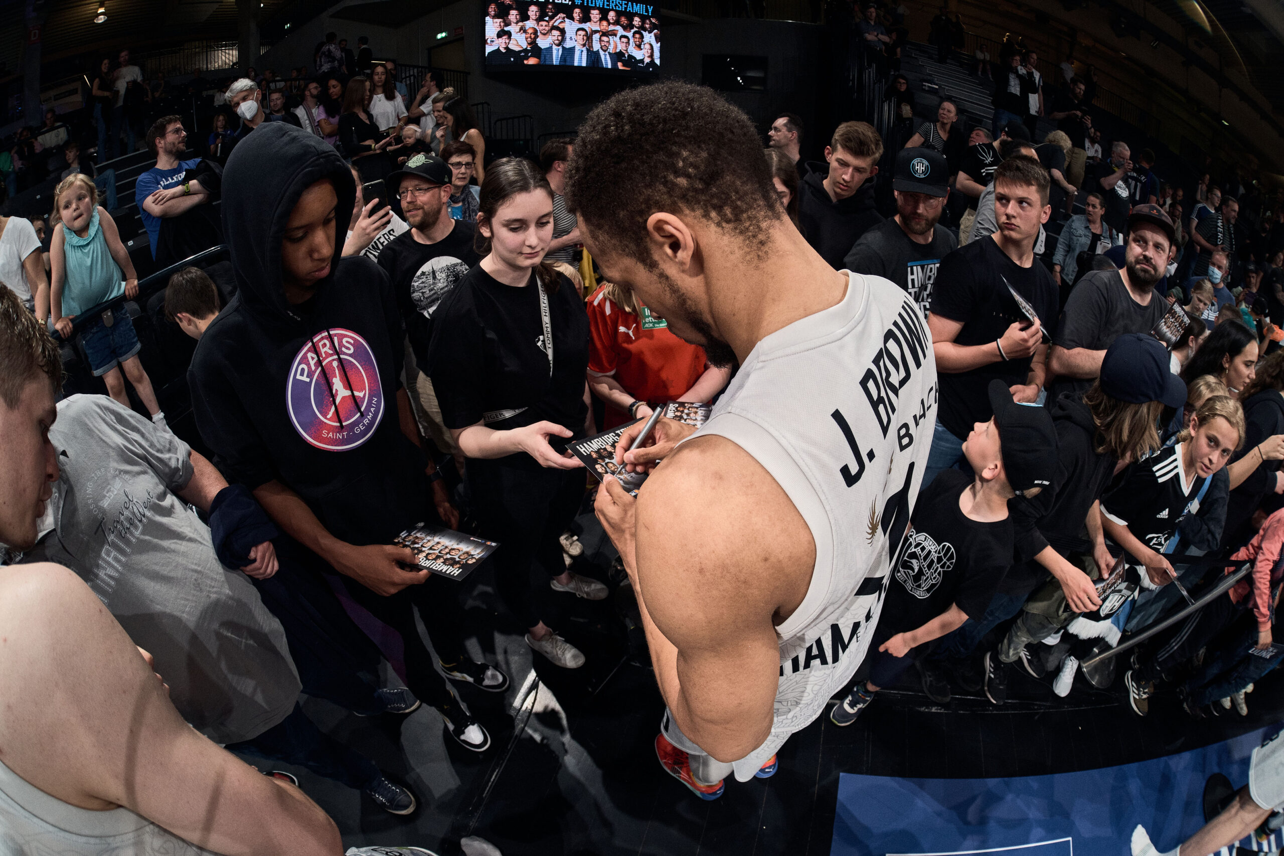 Basketballspieler J. Brown unterschreibt Autogramme für Fans nach einem Spiel in einer Halle