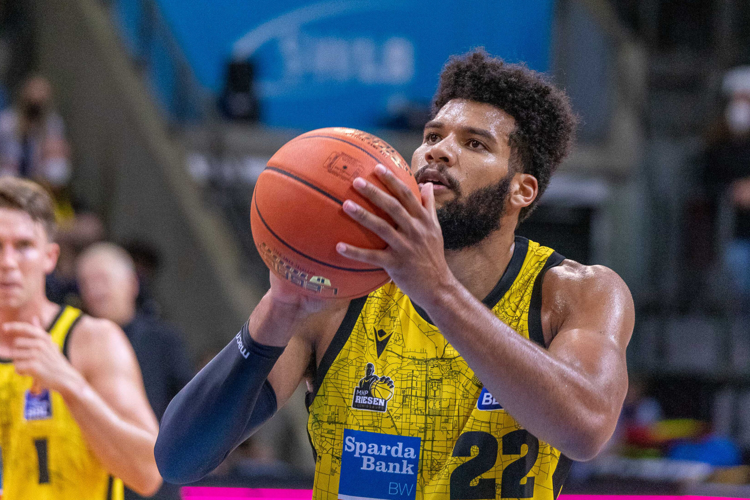 Basketballspieler in gelbem Trikot mit der Nummer 22 bereitet einen Wurf vor