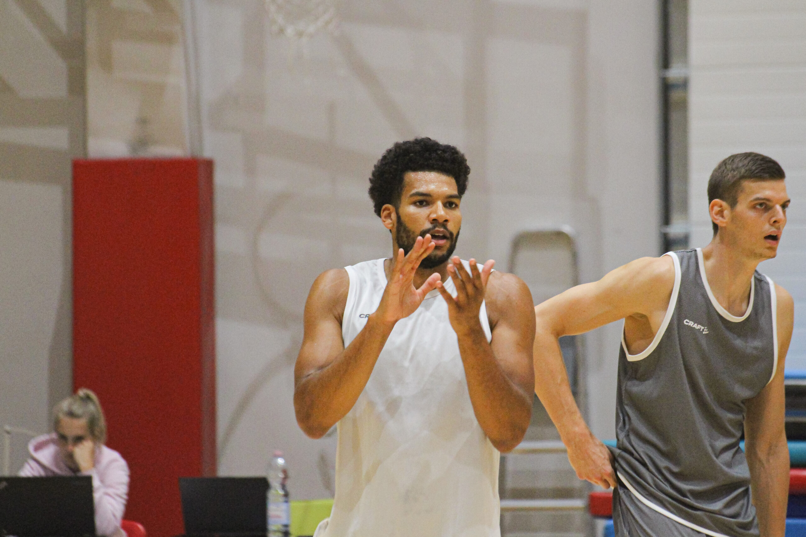 Zwei männliche Basketballspieler in Sportkleidung auf dem Spielfeld, einer klatscht in die Hände