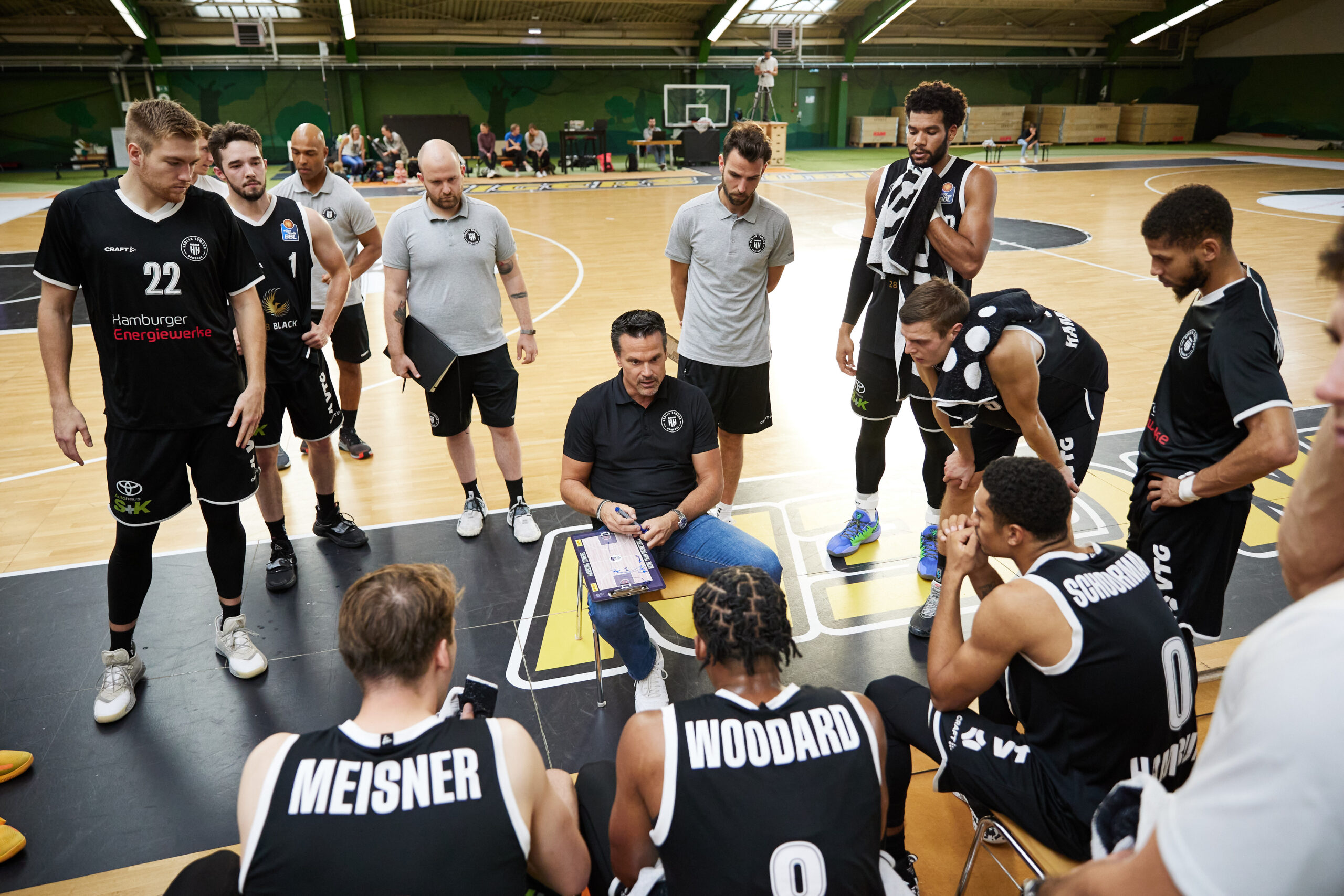 Basketballtrainer erklärt Spielstrategie seinem Team während einer Auszeit auf dem Spielfeld in einer Halle