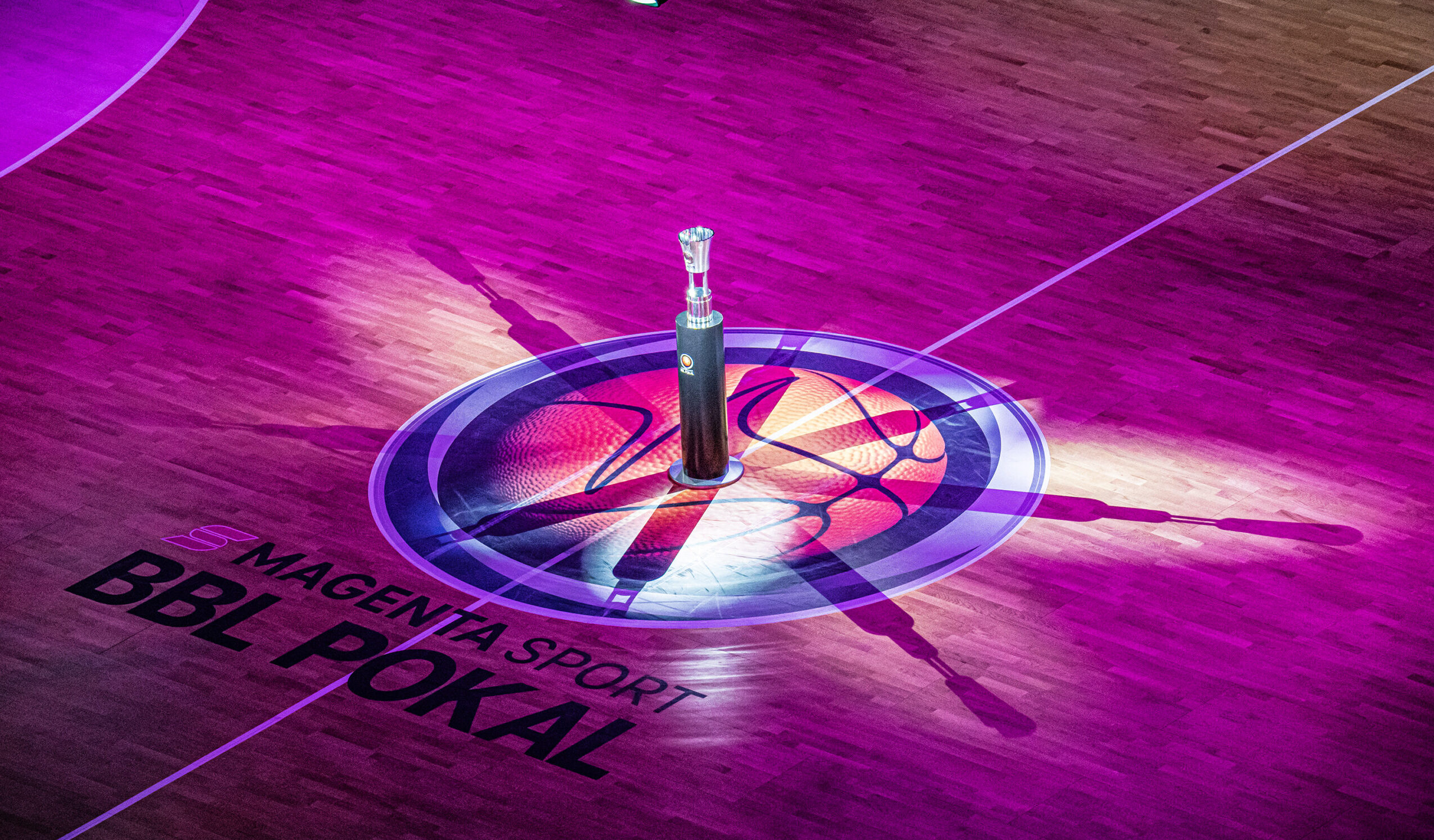 BBL Pokal-Trophäe auf dem beleuchteten Basketballfeld mit 'Magenta Sport BBL Pokal' Schriftzug