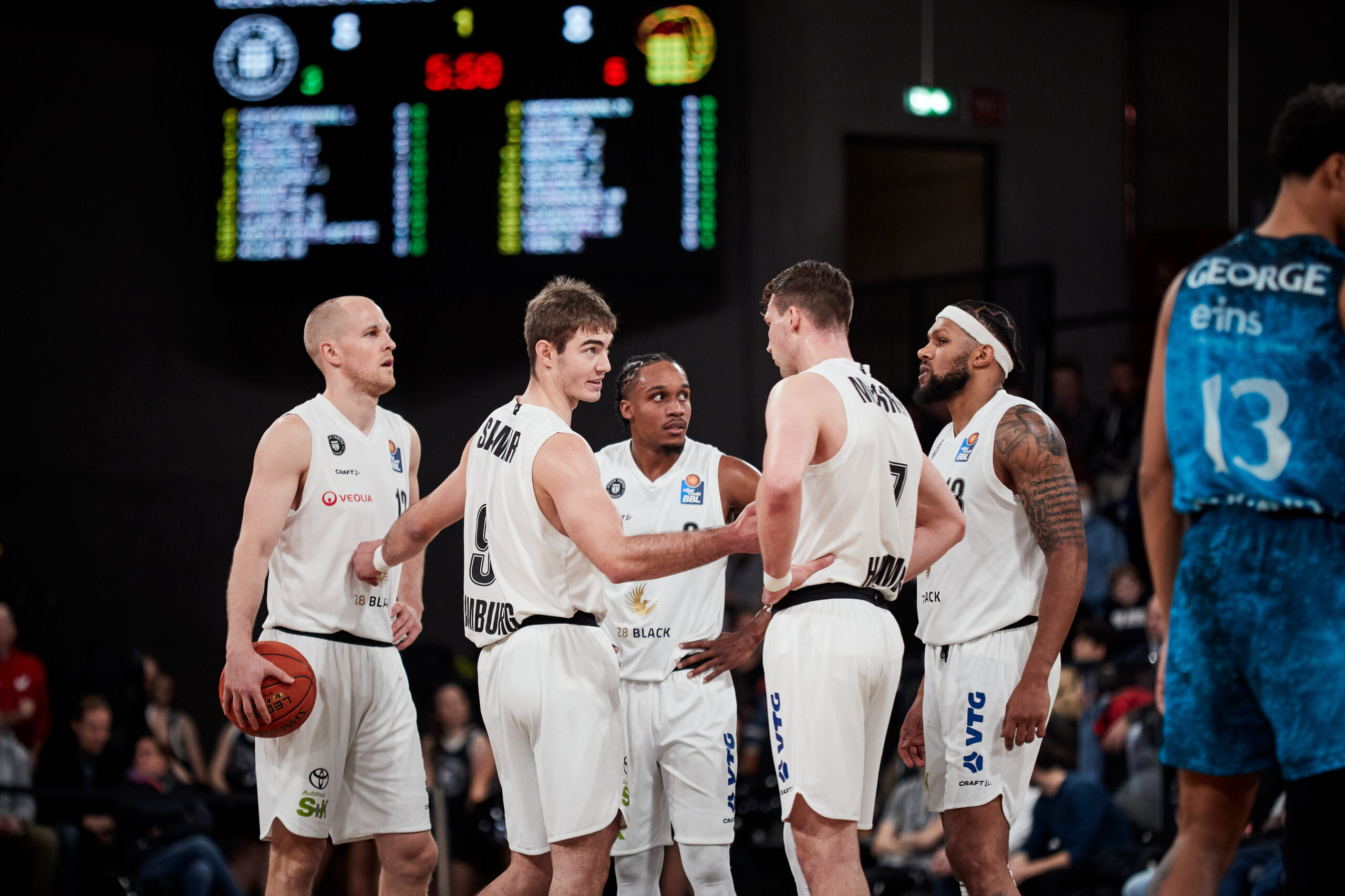 Fünf weiße Basketballspieler in Trikots der Mannschaft Ulm stehen im Kreis und besprechen sich während eines Spiels gegen Chemnitz