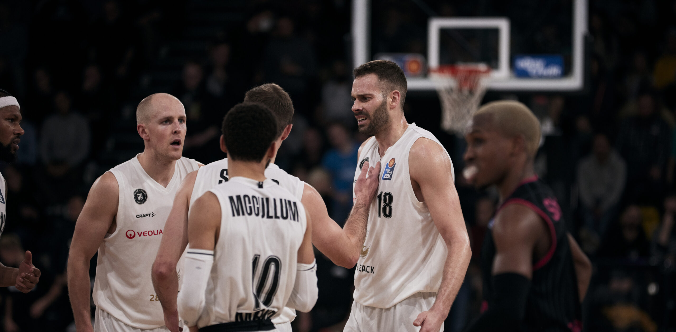 Basketballspieler der Towers in weißen Trikots diskutieren auf dem Spielfeld während eines Spiels gegen Bonn