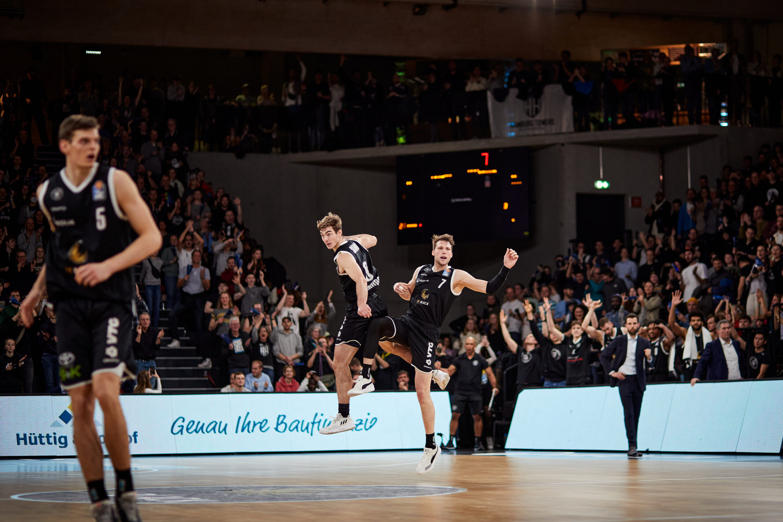 Zwei Basketballspieler der Hamburg Towers in schwarzen Trikots feiern während eines Spiels auf dem Spielfeld, ein Spieler trägt die Nummer 7.