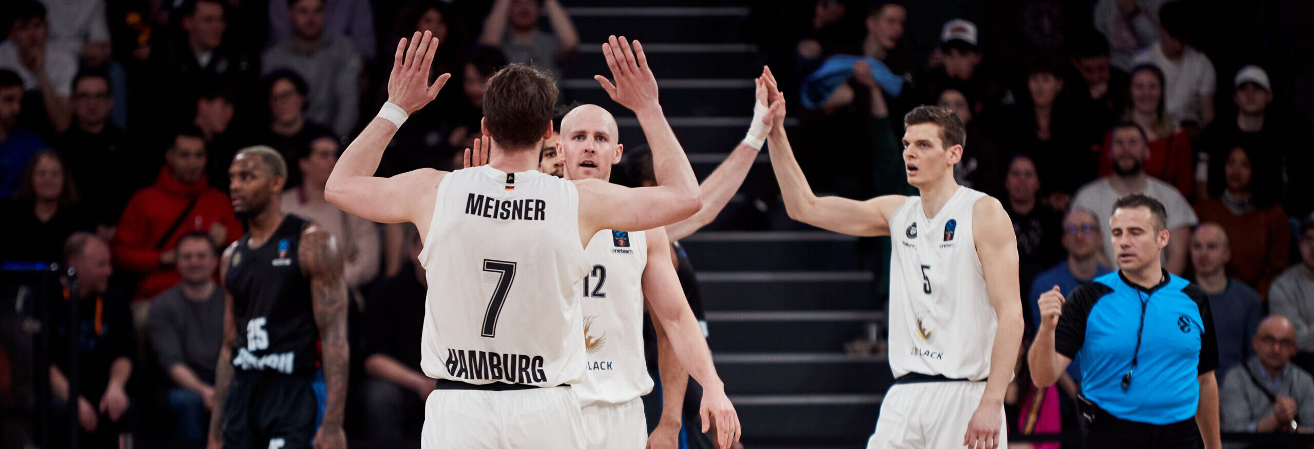 Zwei Basketballspieler der Towers in weißen Trikots geben sich während eines Spiels einen High-Five,