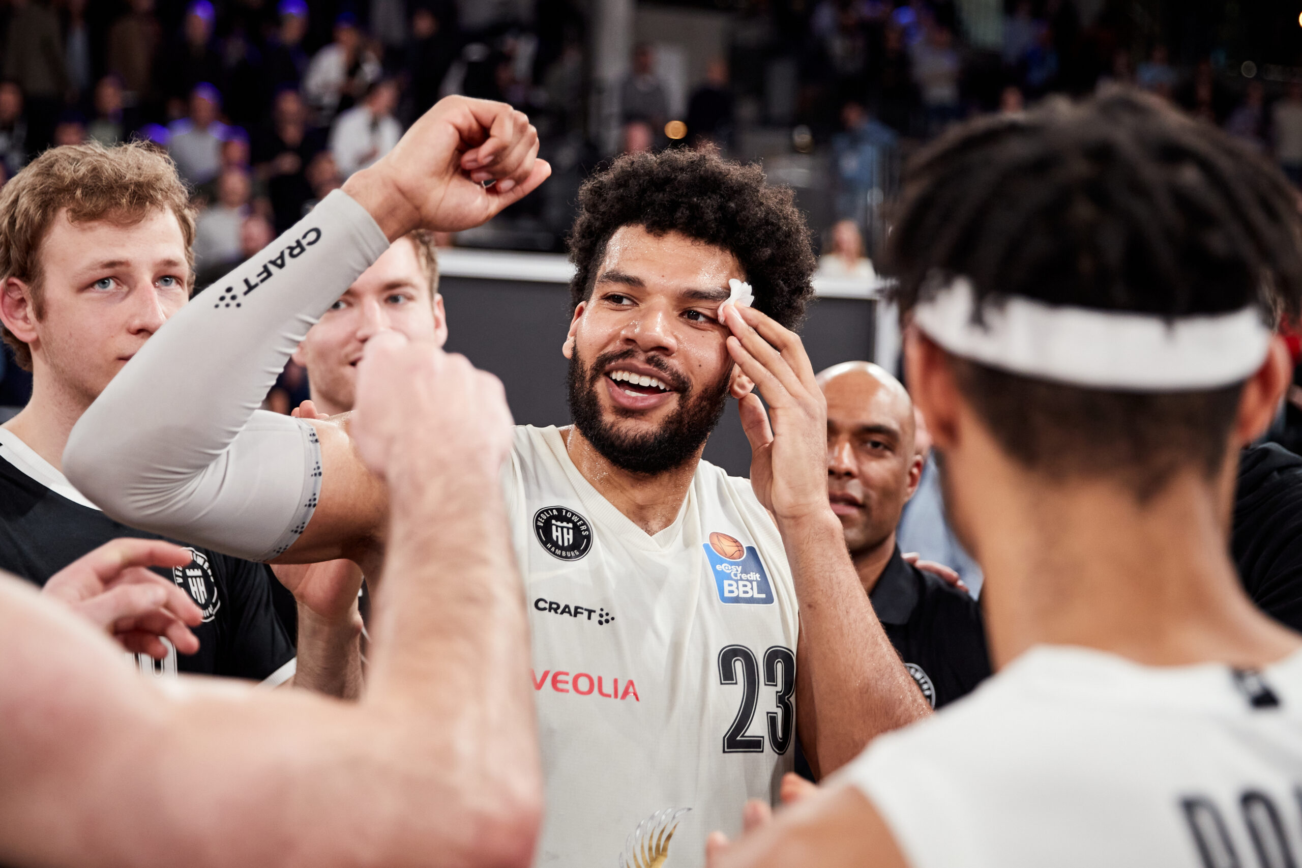 Basketballspieler mit Trikotnummer 23 hebt Arm im Teamkreis während eines Spiels in der BBL