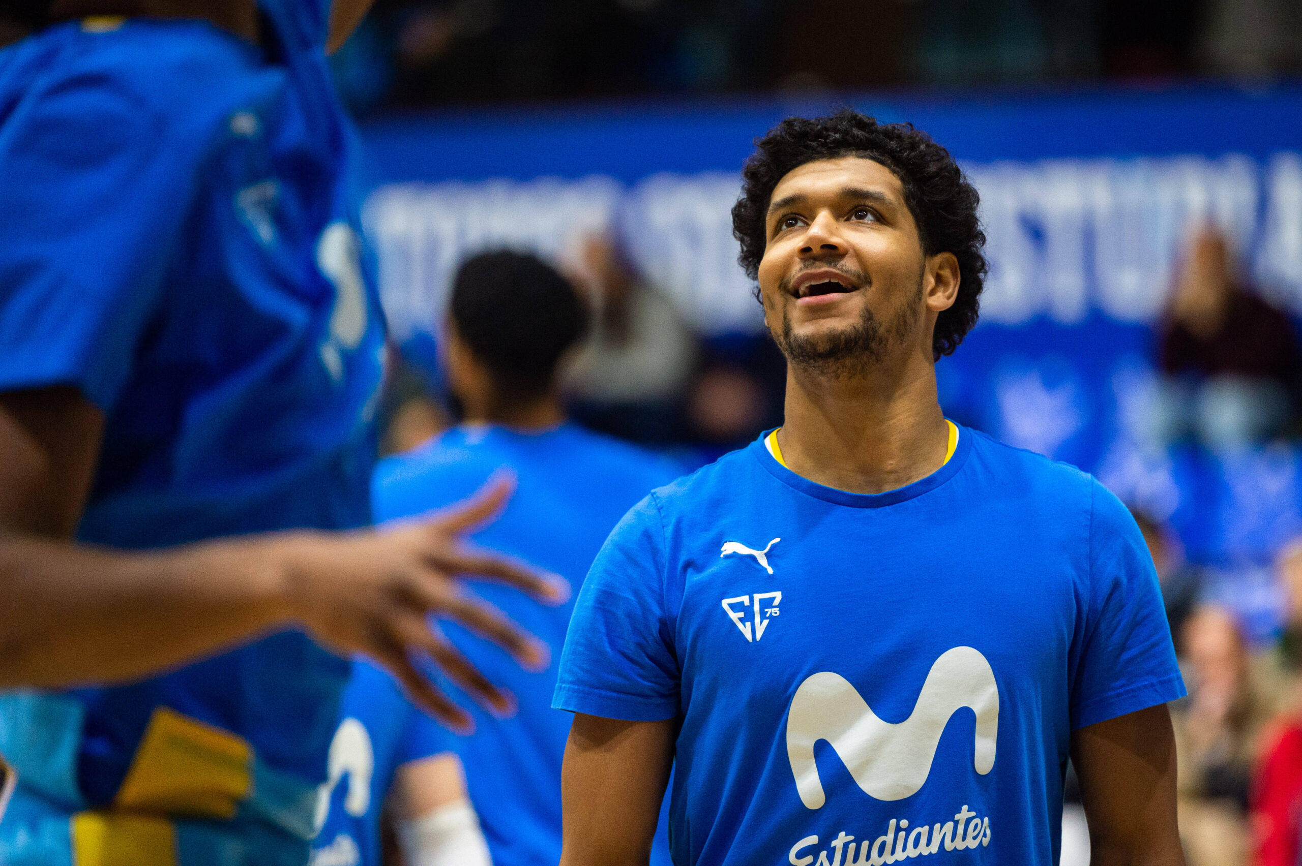 Mann in blauem T-Shirt. Im Hintergrund blaue Bande