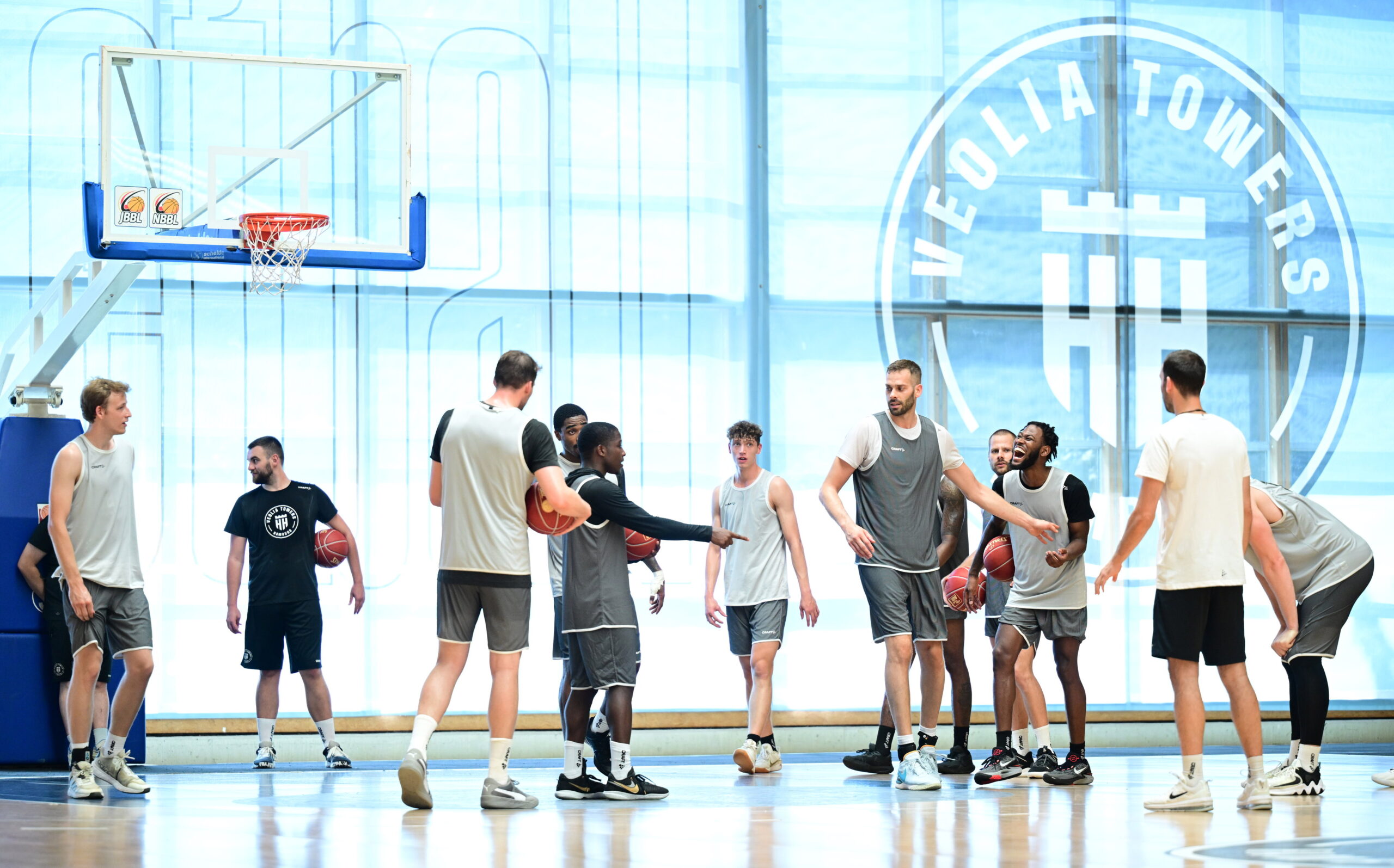 Basketballspieler der Media Towers trainieren in Sportbekleidung auf einem Hallenfeld mit Basketballkorb