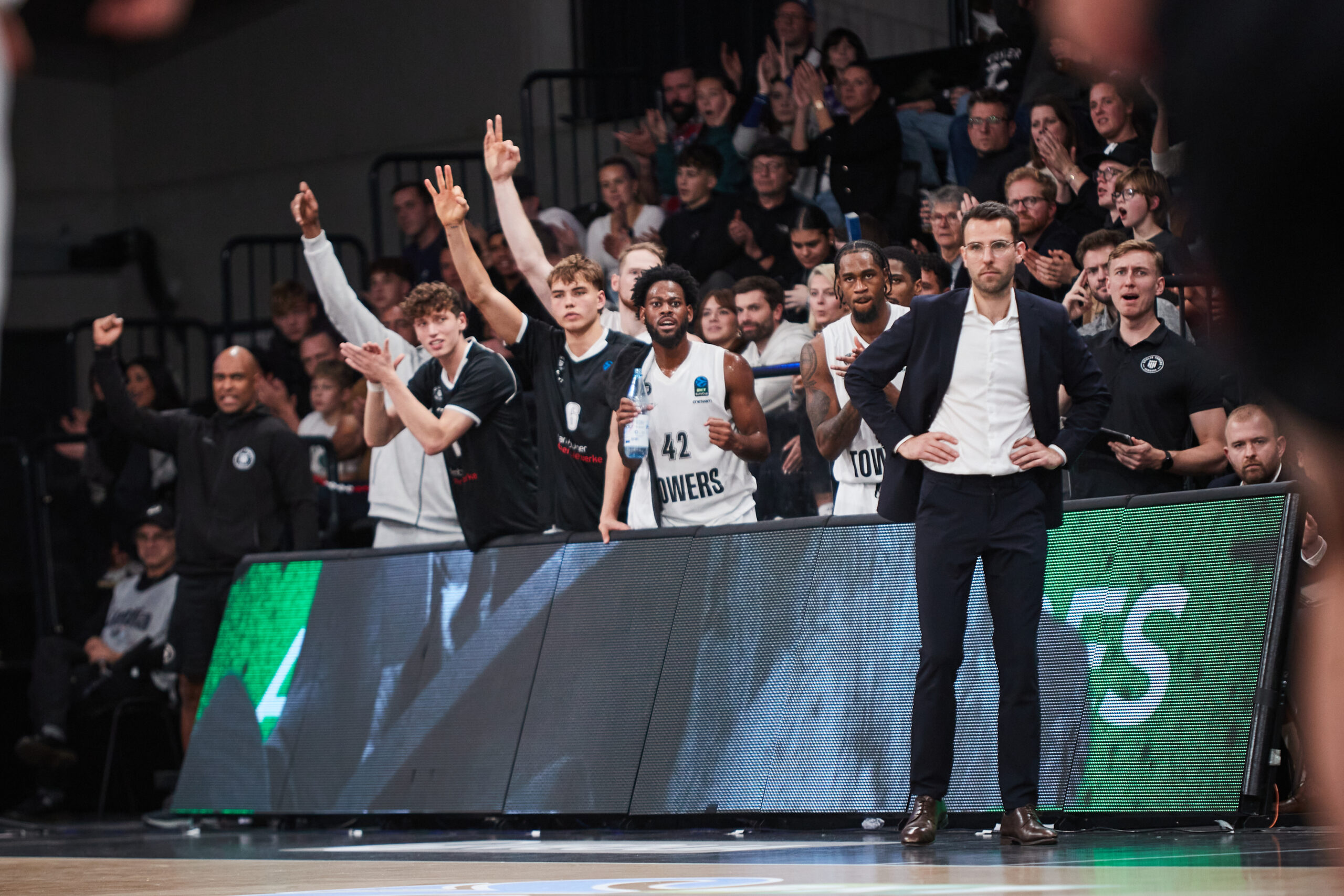 Basketballspieler und Trainer der Towers jubeln an der Seitenlinie während eines Spiels gegen Paris