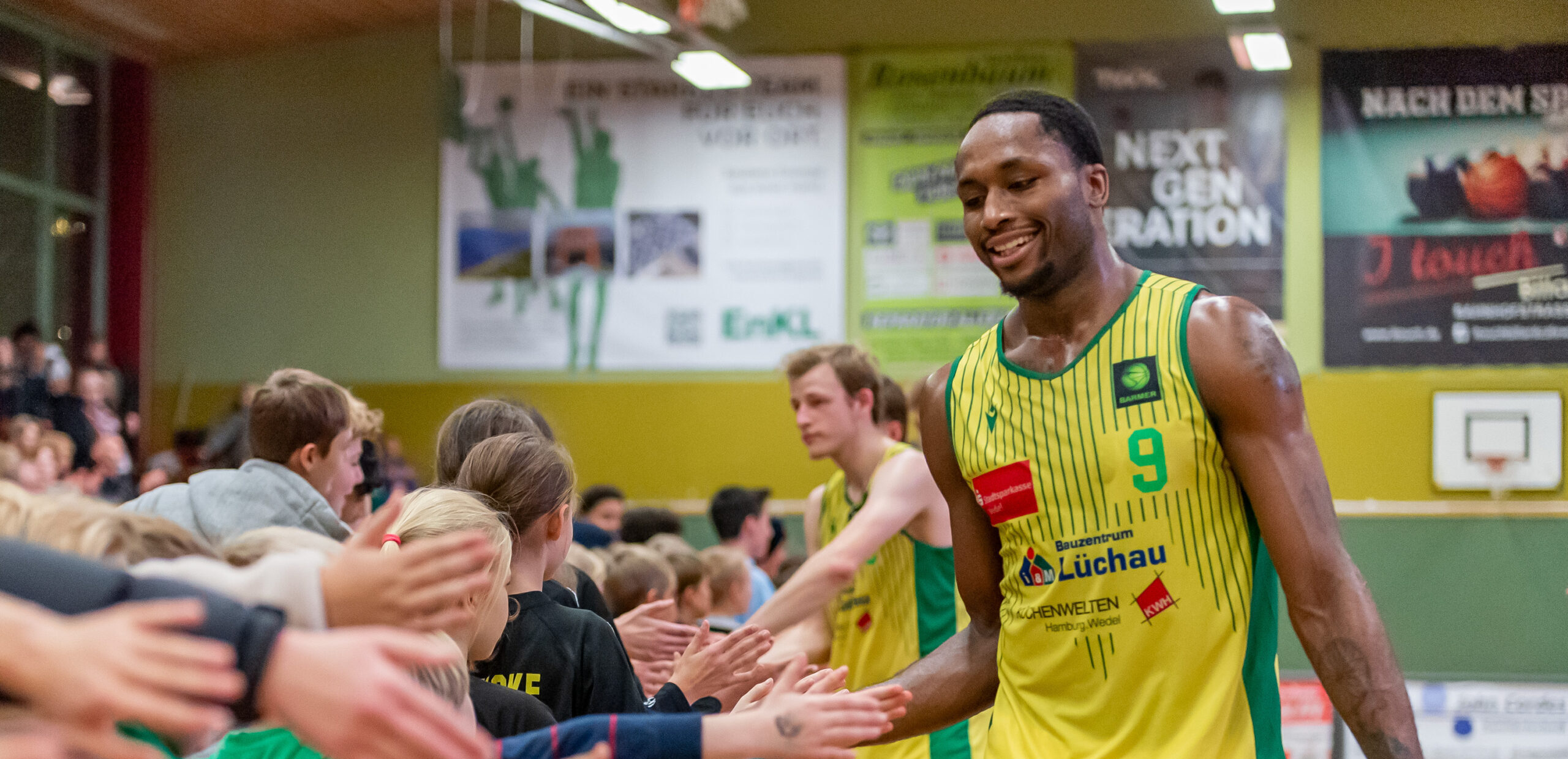 Basketballspieler in gelb-grünem Trikot mit der Nummer 9 gibt Fans in der Halle nach einem Spiel die Hand