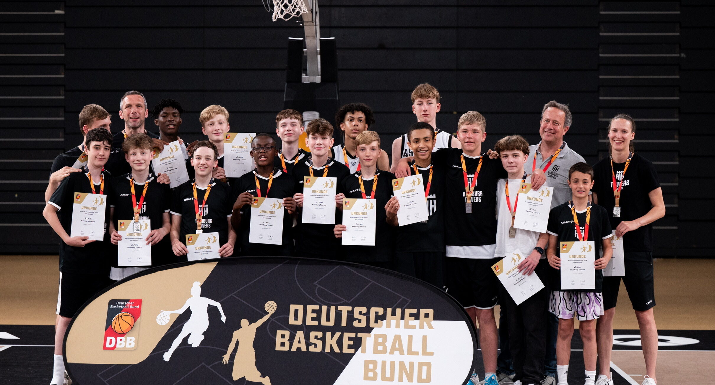 Spieler mit Urkunden und Medaillen vor Basketballkorb