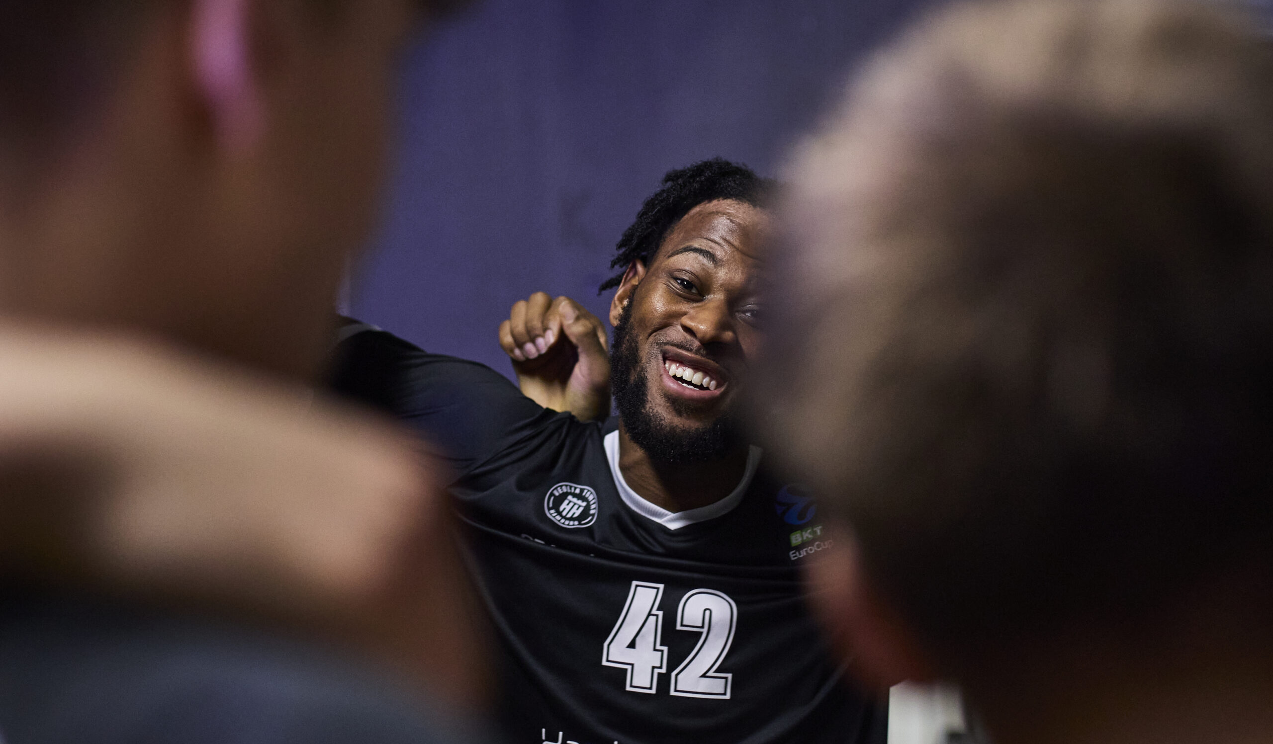 Nahaufnahme von grinsendem Aljami Durham im Teamhuddle