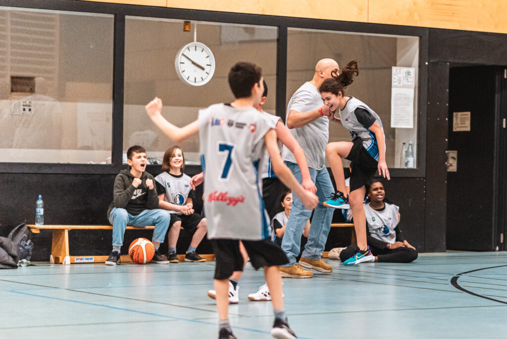 Eine Teilnehmerin der Jr. NBA Hamburg League freut sich mit ihrem Trainer