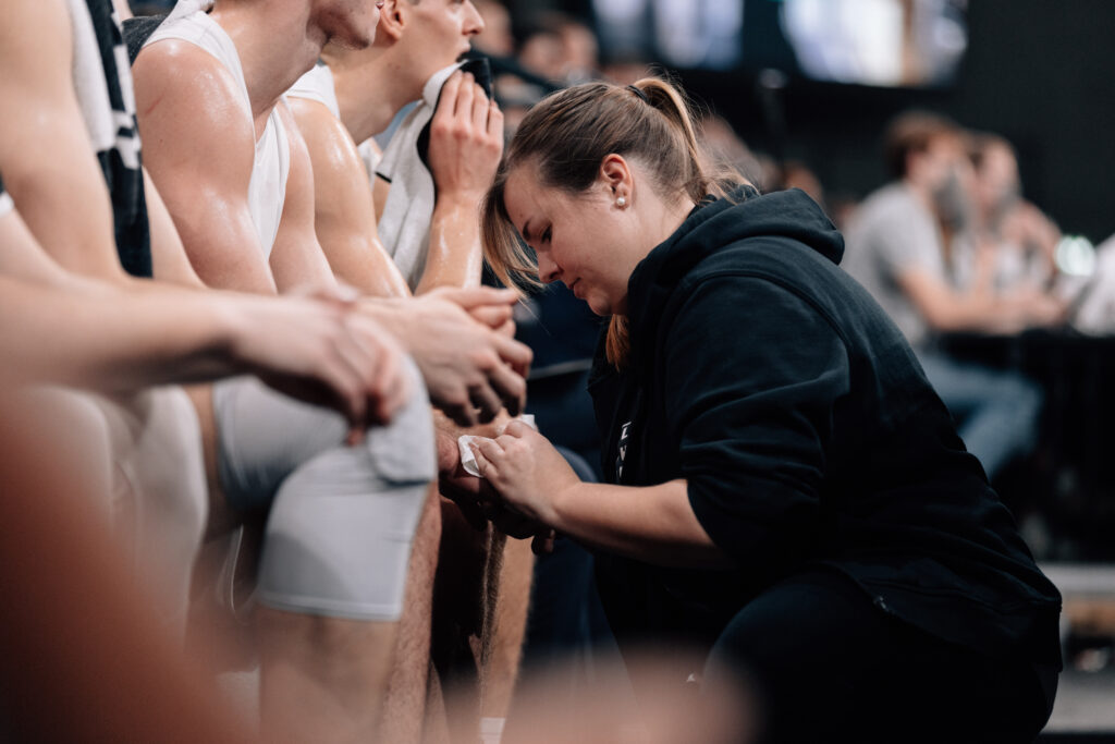 Annika Schlifelner kniet vor Spieler, behandelt Wunde