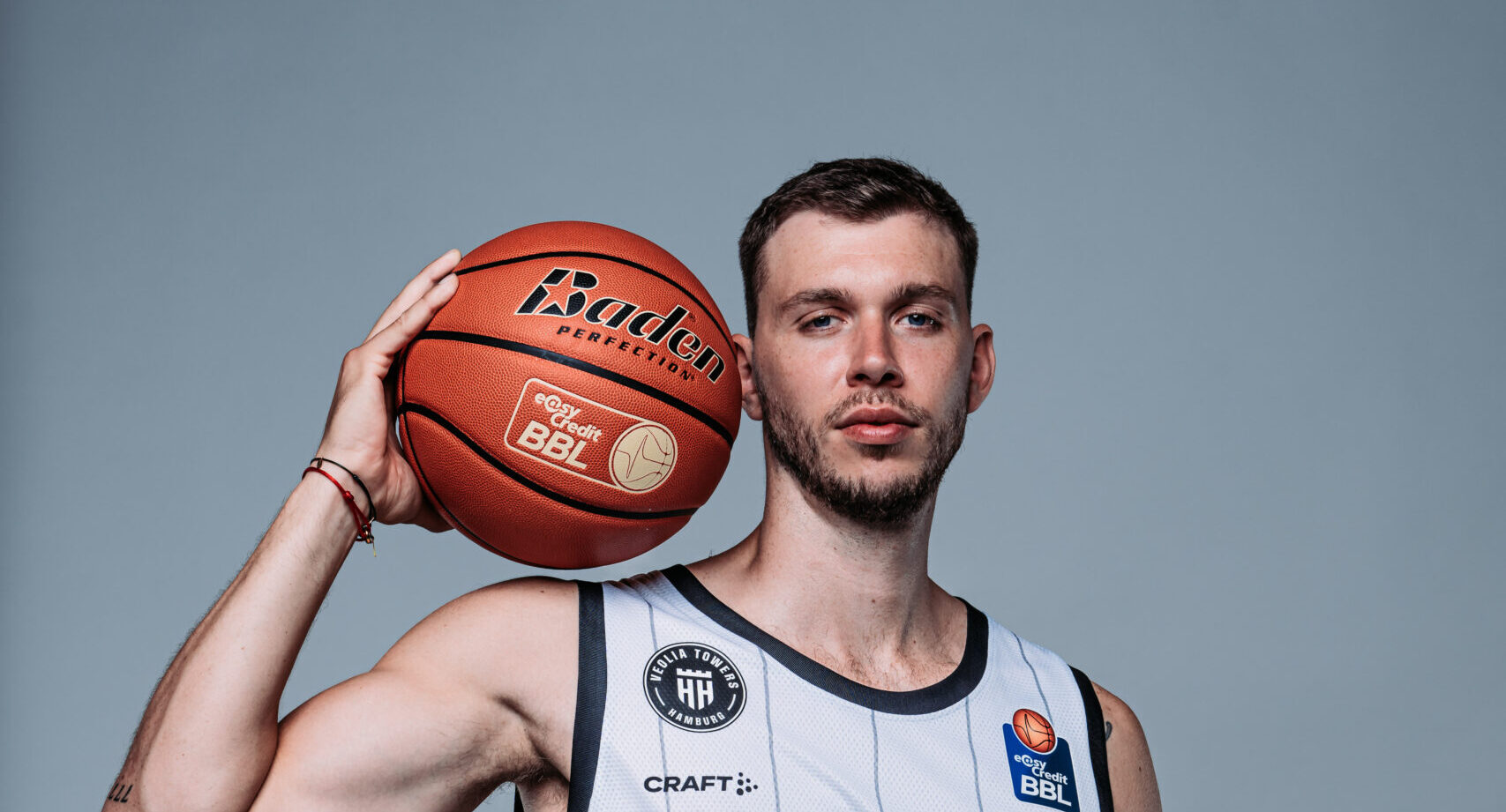 Niklas Wimberg in weißem Trikot mit Ball auf der Schulter