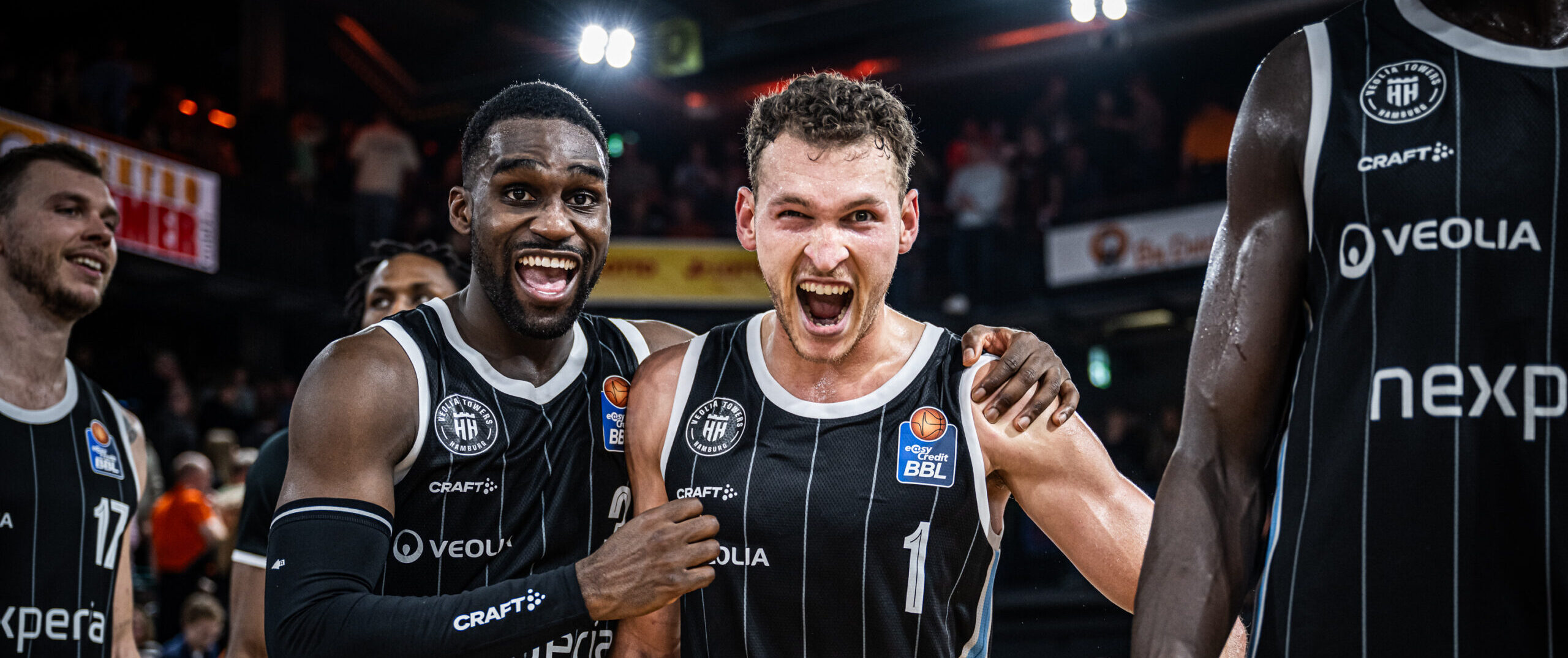 Osaro Rich und Brae Ivey jubeln in schwarzen Trikots jubeln in die Kamera