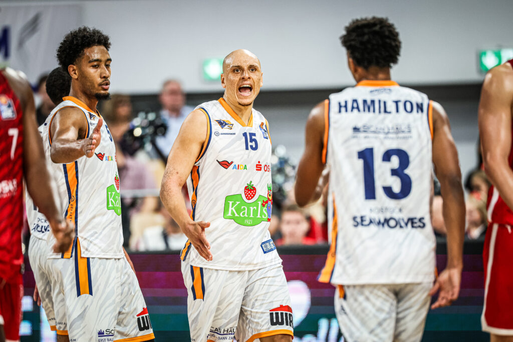 Rostocks Robin Amaize (m.) und D’Shawn Schwartz (l.) laufen auf Bryce Hamilton (r.) zu