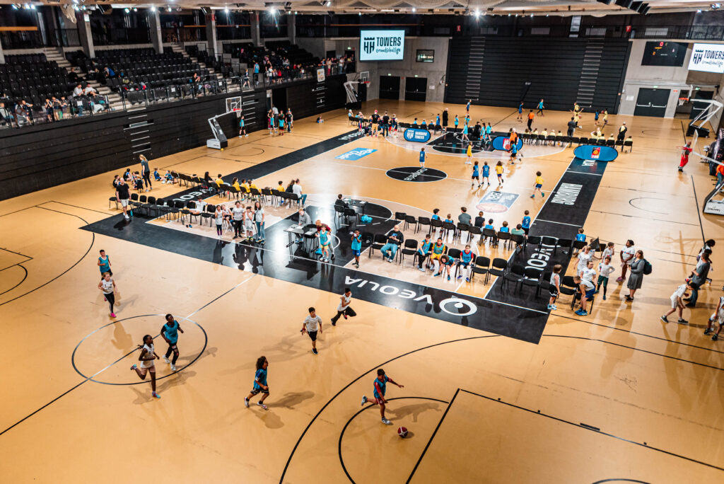 Großaufnahme einer Sporthalle in der Kinder Basketball spielen
