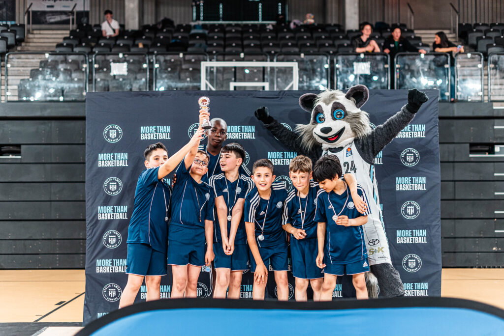 Kinder jubeln mit einem Waschbär-Maskottchen und Pokal