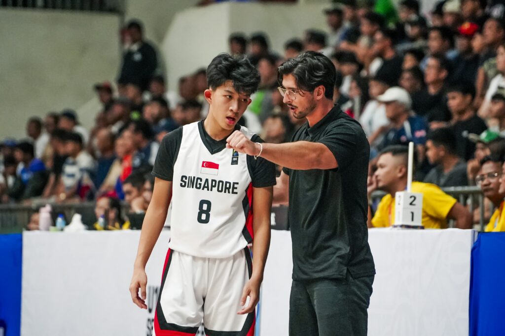 Trainer Leo Aris im Gespräch mit Jugendlichem im Trikot mit der Aufschrift "Singapore"