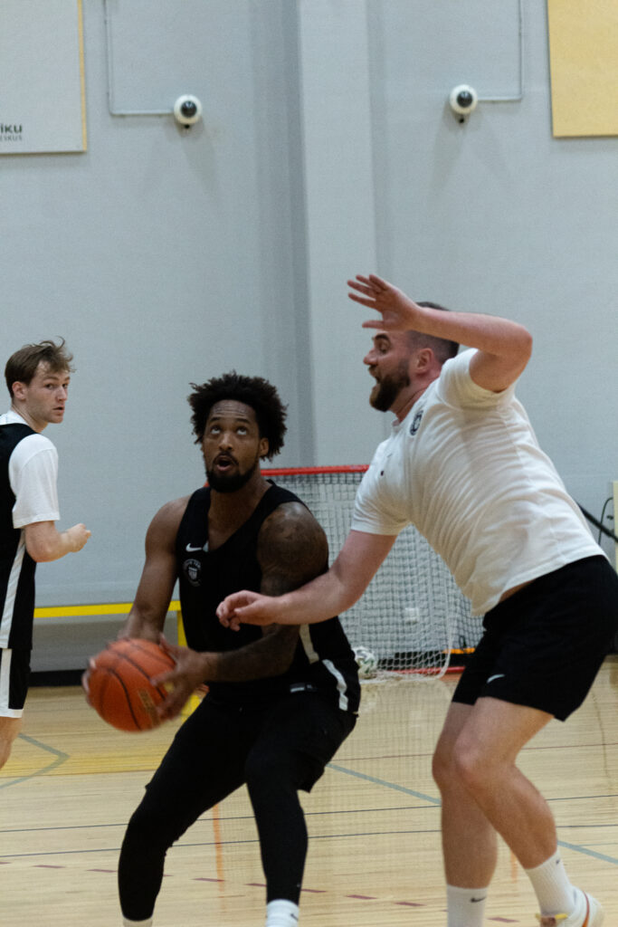 Basketballspieler in schwarzer Kleidung im Training mit Trainer