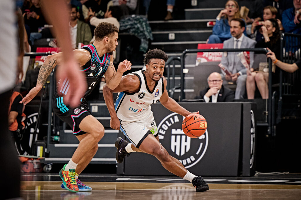 Basketballspieler in weißem Trikot mit Ball in der Hand