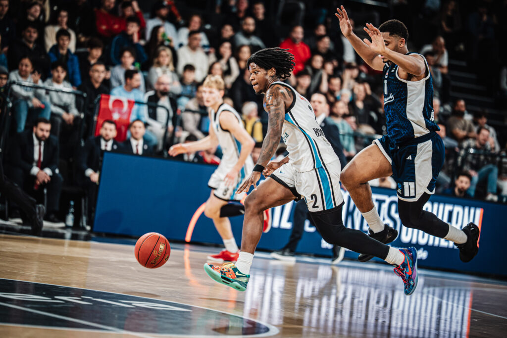 Basketballspieler in weißem Trikot dribbelt den Ball vorwärts