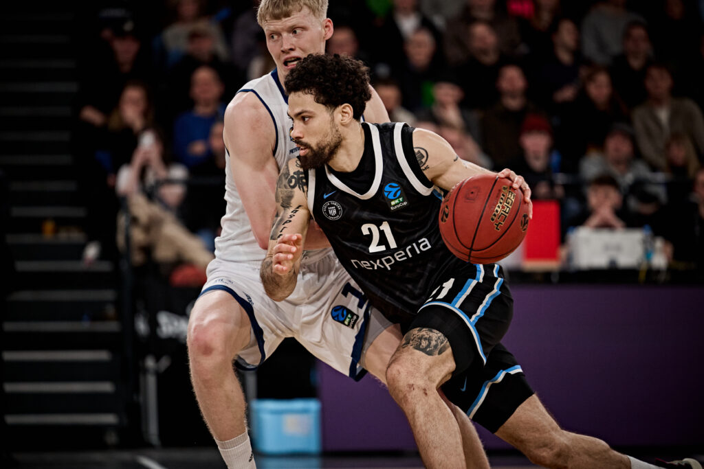 Zwei Basketballspieler in Aktion, einer mit Ball in schwarzem Trikot mit der Nummer 21 und Schriftzug 'nexperia'