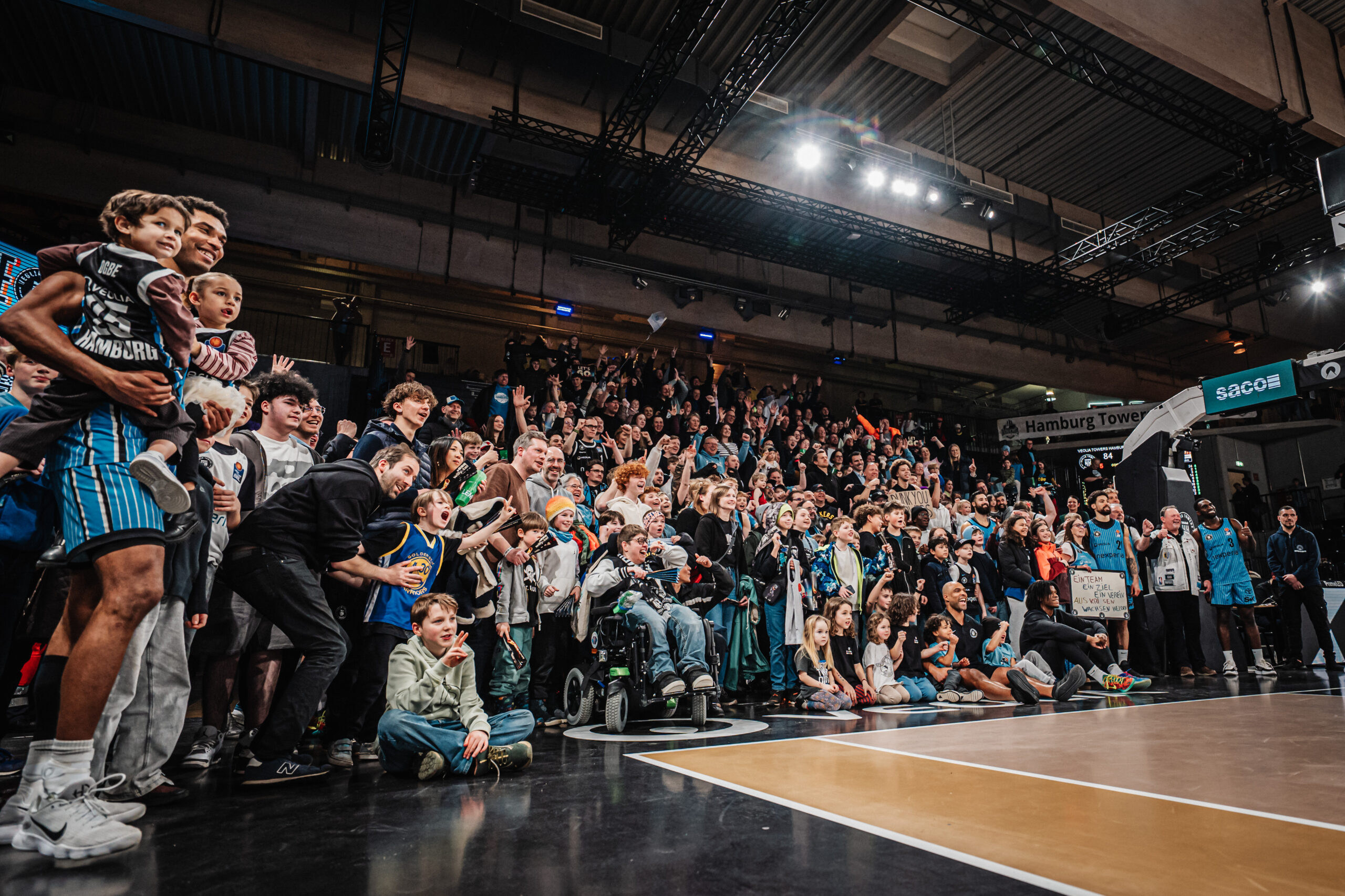 Große Menschenmenge auf Tribüne und am Spielfeldrand in einer Halle bei einem Basketballspiel