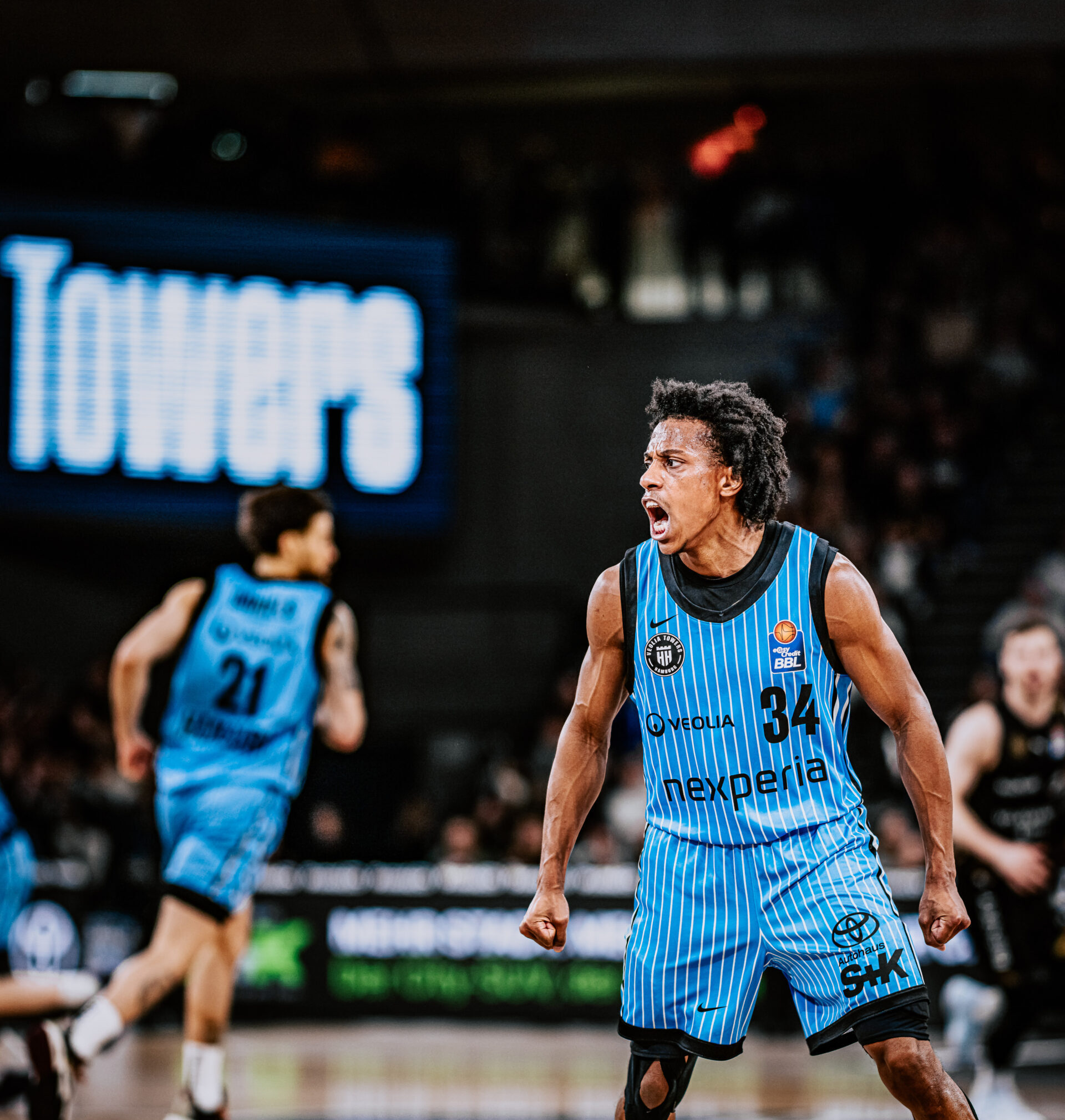 Basketballspieler mit blau-weiß gestreiftem Trikot mit der Nummer 34 steht angespannt auf dem Spielfeld.