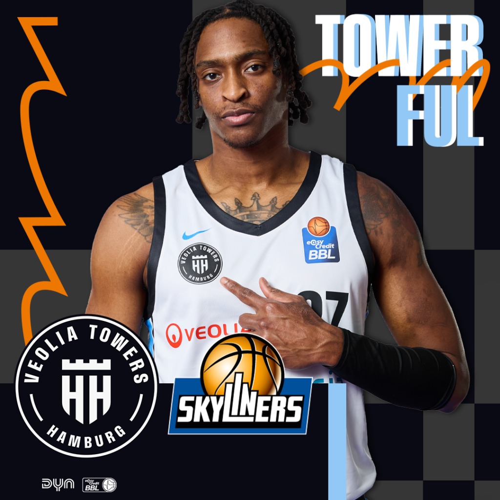 Basketballspieler mit schwarzem Trikot der Veolia Towers Hamburg zeigt mit der rechten Hand auf die Brust, im Hintergrund Schriftzug 'TOWER FUL' und Logos der Veolia Towers Hamburg und Skyliners.