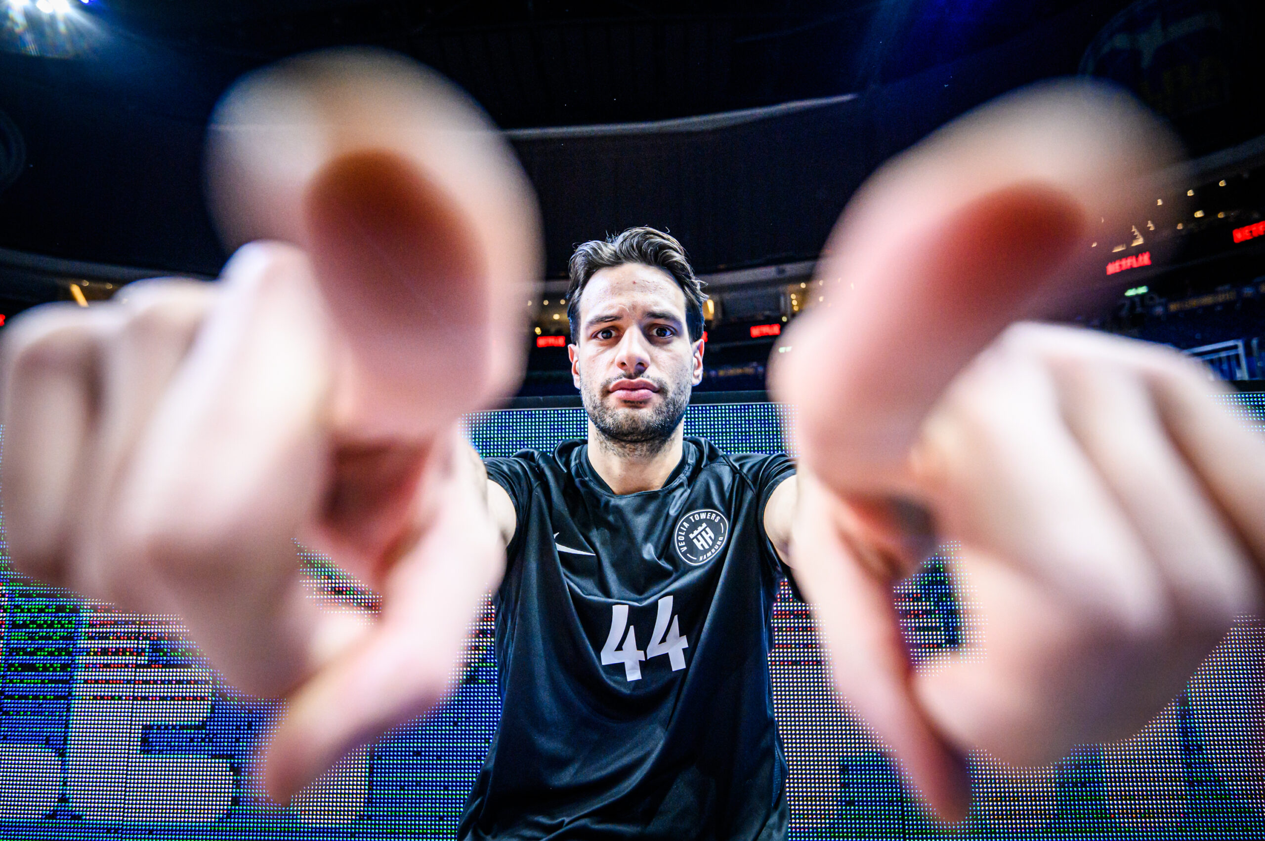 Sportler mit Trikotnummer 44 zeigt beide Zeigefinger nach vorne in einer Sporthalle